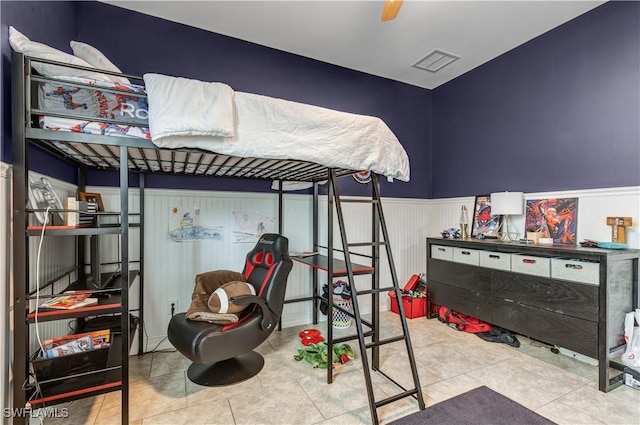 bedroom with a wainscoted wall, tile patterned floors, and visible vents