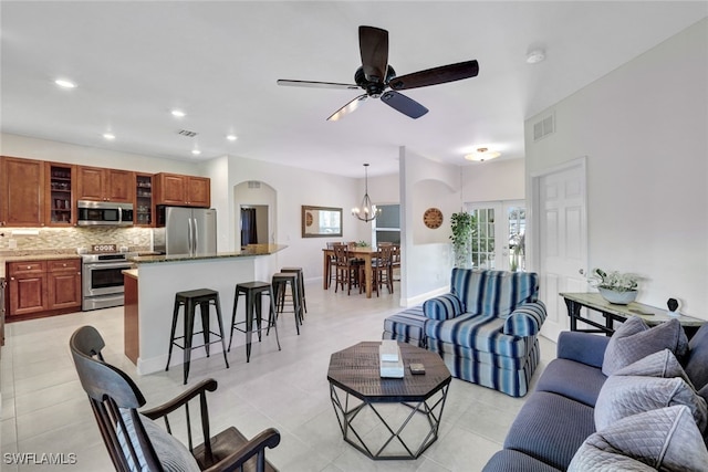 living area featuring light tile patterned floors, ceiling fan with notable chandelier, visible vents, and recessed lighting