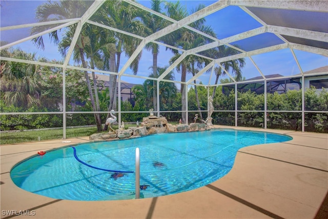 view of pool with glass enclosure and a patio