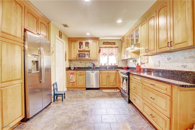 kitchen with backsplash, sink, dark stone countertops, light brown cabinetry, and stainless steel appliances