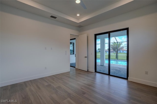 spare room featuring hardwood / wood-style floors, ceiling fan, and a tray ceiling