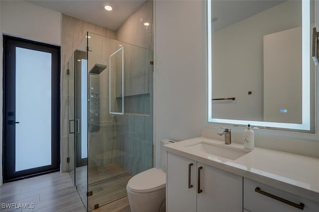 bathroom featuring hardwood / wood-style floors, vanity, toilet, and a shower with shower door