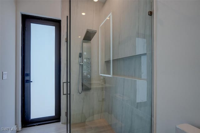 bathroom with a shower with door and toilet