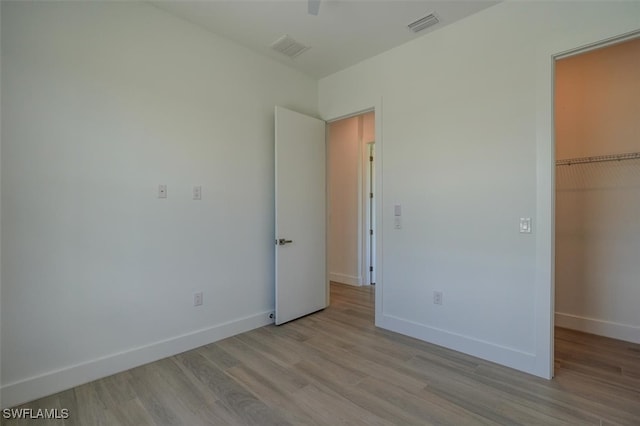 unfurnished bedroom featuring light wood-type flooring, a spacious closet, and a closet