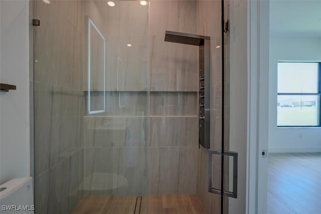 bathroom with a shower with shower door and toilet