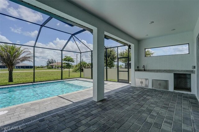 view of pool featuring a lawn, glass enclosure, sink, a patio area, and area for grilling