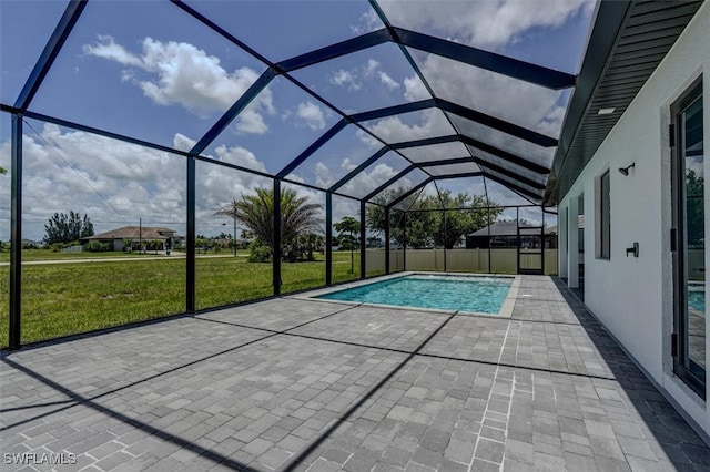 view of swimming pool featuring glass enclosure, a patio area, and a yard