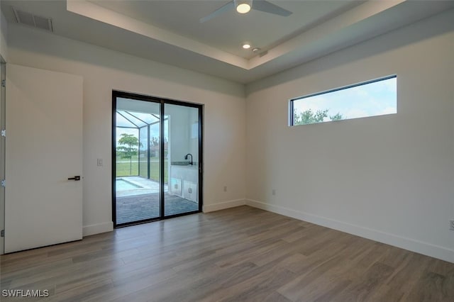 empty room featuring light hardwood / wood-style flooring, a raised ceiling, and ceiling fan