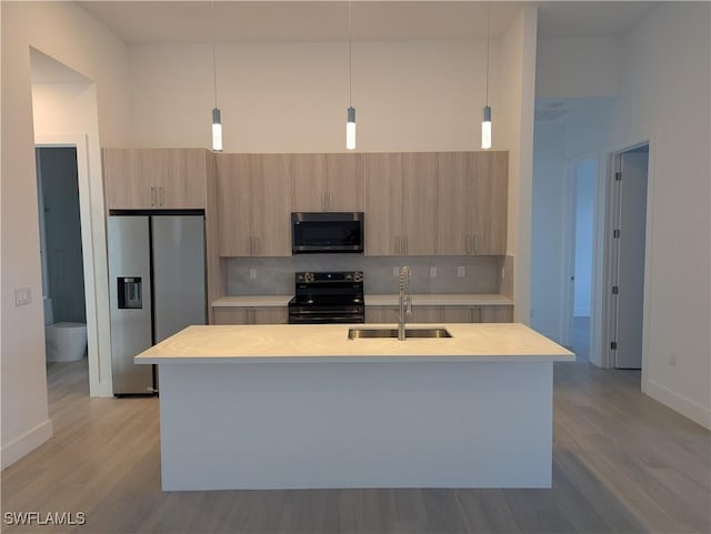 kitchen with sink, stainless steel appliances, tasteful backsplash, pendant lighting, and a kitchen island with sink