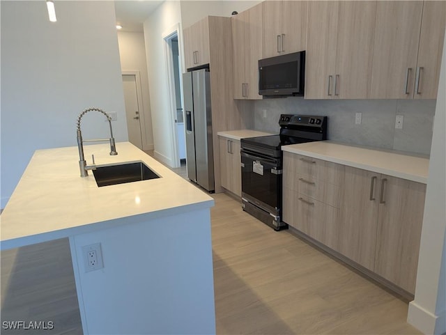 kitchen with stainless steel refrigerator with ice dispenser, black range with electric cooktop, sink, light brown cabinets, and an island with sink