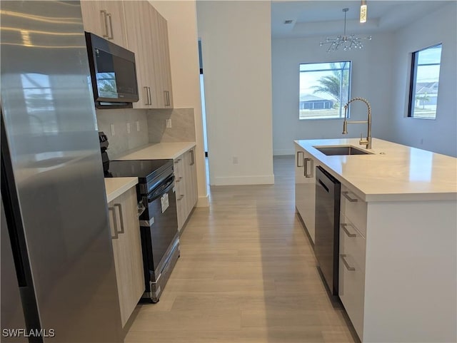 kitchen featuring range with electric cooktop, sink, stainless steel fridge, an island with sink, and dishwashing machine