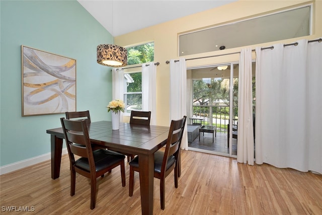 dining space with high vaulted ceiling and light hardwood / wood-style flooring