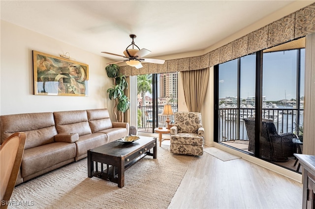 living room with light hardwood / wood-style flooring, ceiling fan, and a water view