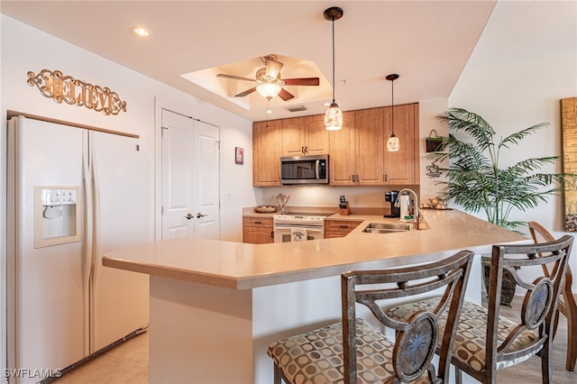 kitchen with sink, a breakfast bar area, ceiling fan, kitchen peninsula, and white appliances