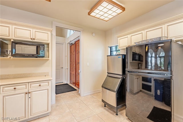 kitchen with light tile patterned floors, black appliances, and cream cabinetry