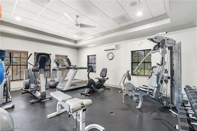 gym featuring a paneled ceiling, ornamental molding, a raised ceiling, a wall unit AC, and ceiling fan