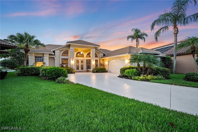 mediterranean / spanish house featuring french doors, a garage, and a yard