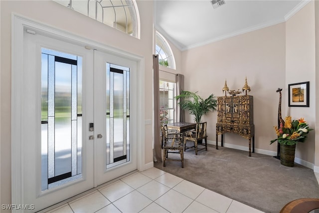 foyer entrance with french doors, light carpet, elevator, ornamental molding, and a towering ceiling