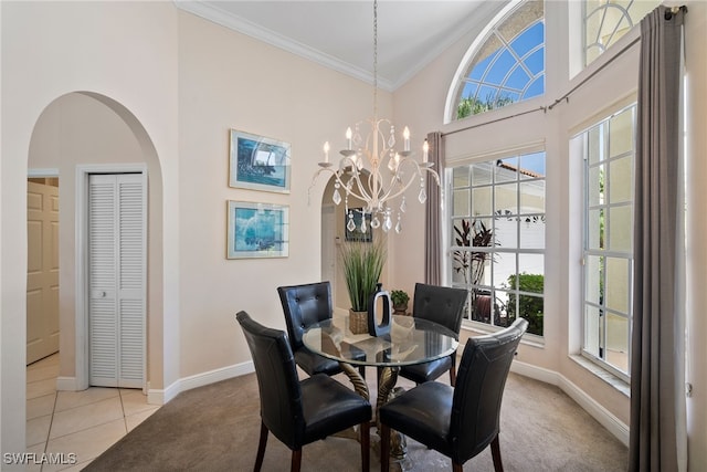 dining room with crown molding, a towering ceiling, a chandelier, and light carpet