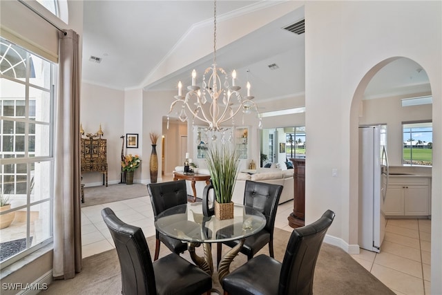 dining space featuring an inviting chandelier, a healthy amount of sunlight, ornamental molding, and light tile patterned floors