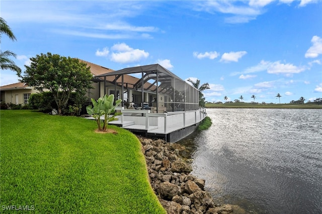 view of dock with a yard, a water view, and glass enclosure