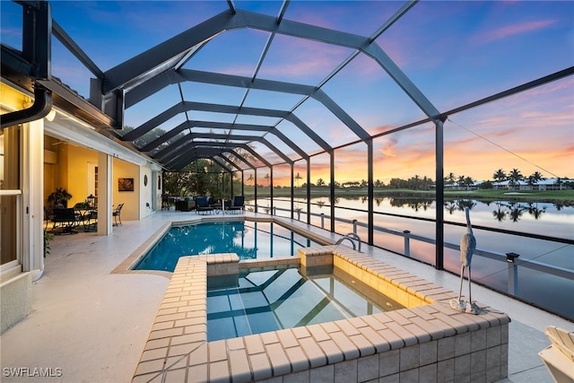 pool at dusk featuring a water view, glass enclosure, and a patio area