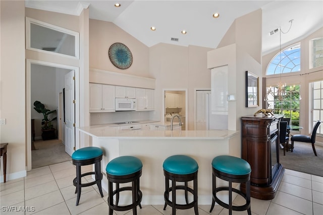 kitchen featuring a notable chandelier, a kitchen breakfast bar, sink, and white cabinets