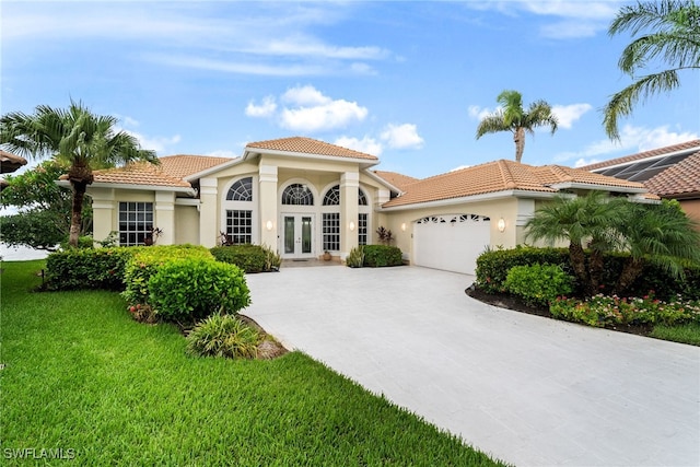 mediterranean / spanish home featuring a garage, a front lawn, and french doors