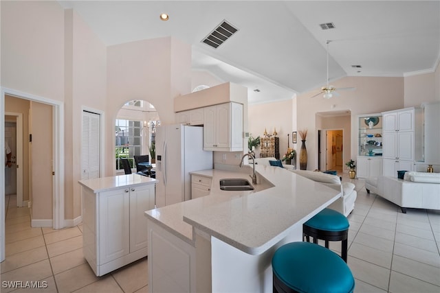 kitchen with sink, white refrigerator with ice dispenser, kitchen peninsula, and white cabinets