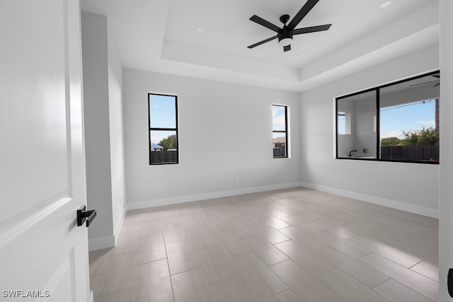 spare room featuring a tray ceiling, plenty of natural light, and ceiling fan