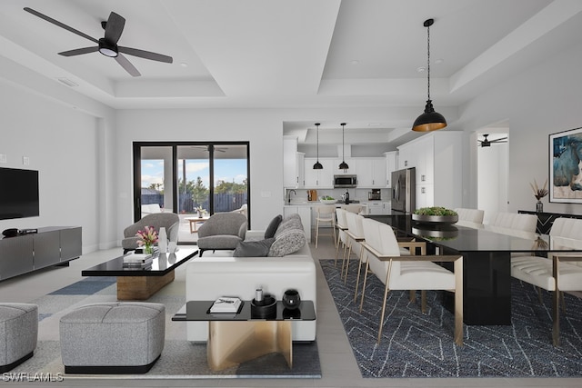 living room with ceiling fan, sink, and a tray ceiling