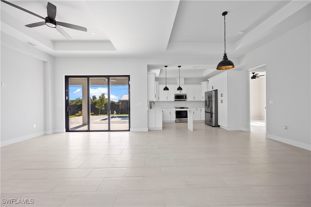 unfurnished living room with light tile patterned floors, ceiling fan, and a raised ceiling