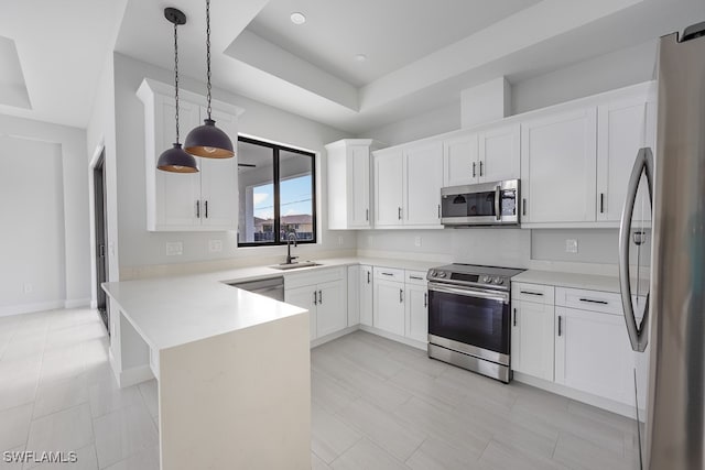 kitchen with appliances with stainless steel finishes, kitchen peninsula, pendant lighting, light tile patterned floors, and a tray ceiling