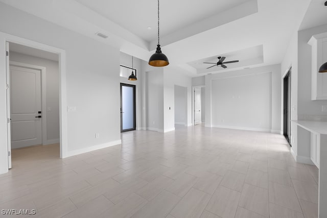 tiled spare room with ceiling fan and a raised ceiling