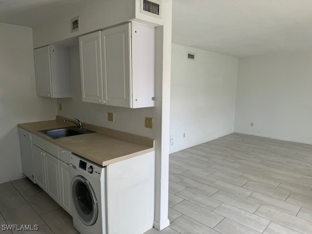 kitchen featuring washer / clothes dryer, sink, light hardwood / wood-style flooring, and white cabinets