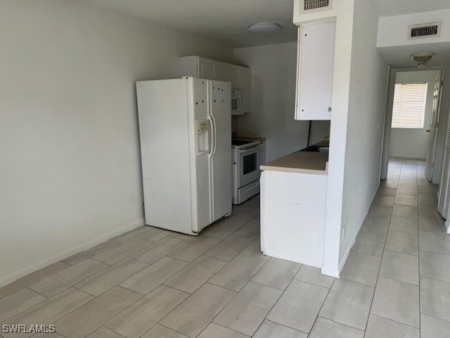 kitchen with white cabinets and white appliances