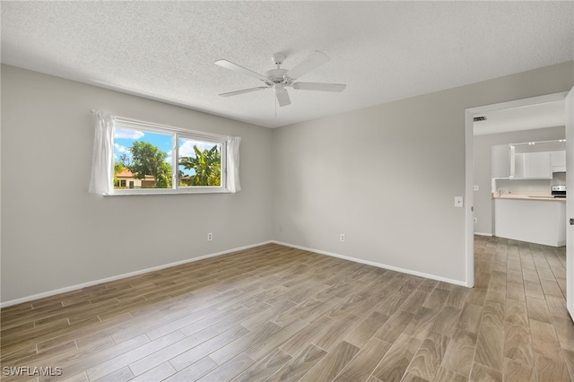 spare room featuring ceiling fan, a textured ceiling, and light hardwood / wood-style flooring