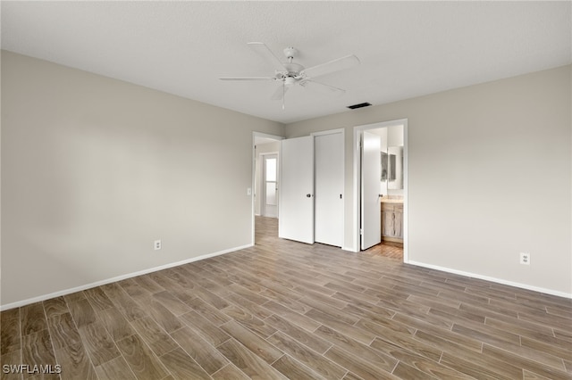 unfurnished bedroom with ensuite bath, ceiling fan, and hardwood / wood-style floors