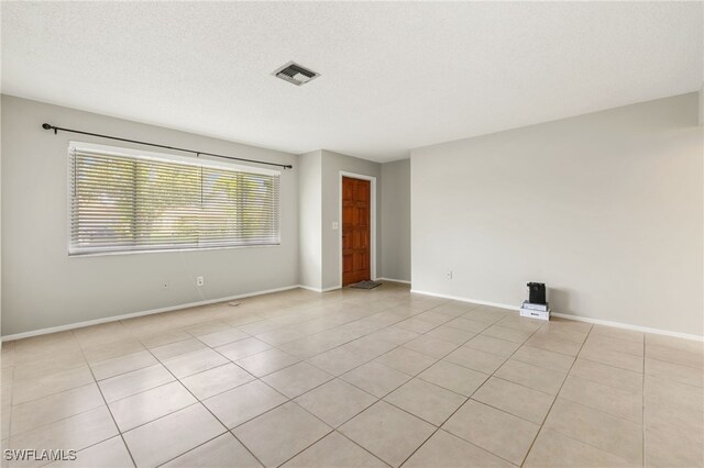 tiled spare room with a textured ceiling