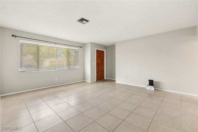 tiled spare room featuring a textured ceiling