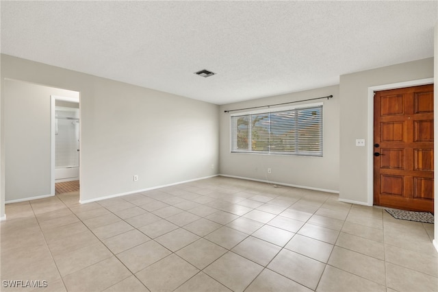 spare room featuring light tile patterned floors and a textured ceiling