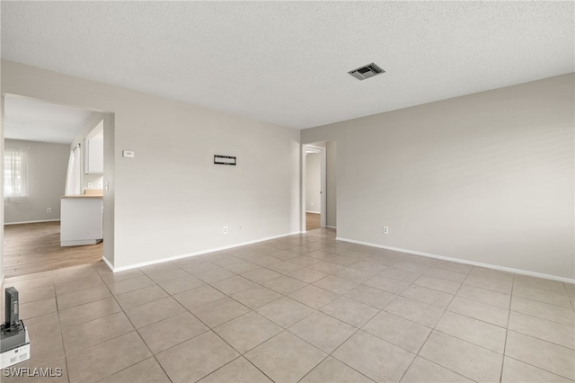 unfurnished room featuring light tile patterned flooring and a textured ceiling