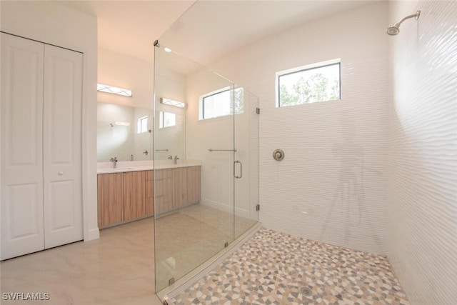 bathroom featuring a shower with shower door, double vanity, and tile patterned flooring