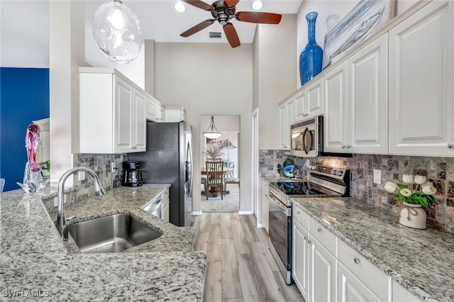 kitchen featuring white cabinetry, sink, pendant lighting, and appliances with stainless steel finishes