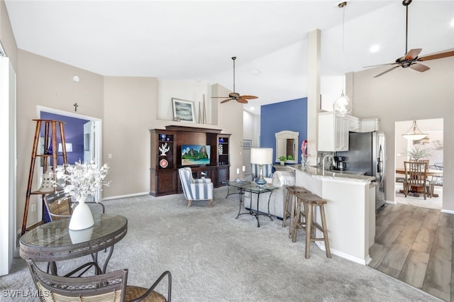 kitchen with high vaulted ceiling, white cabinets, a kitchen breakfast bar, ceiling fan, and kitchen peninsula