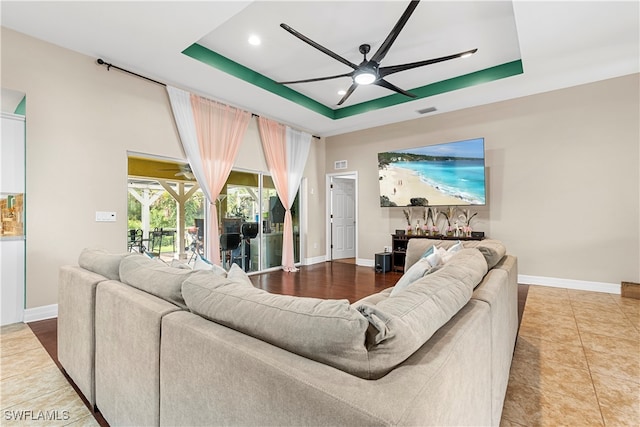 living room featuring ceiling fan, a raised ceiling, and tile patterned floors