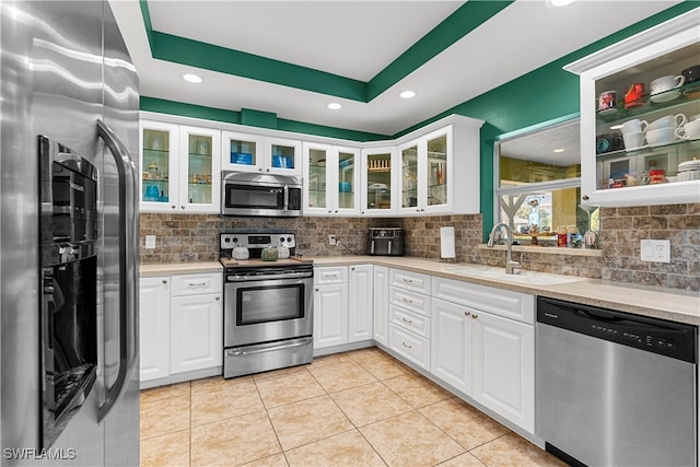 kitchen featuring light tile patterned floors, appliances with stainless steel finishes, sink, and white cabinetry