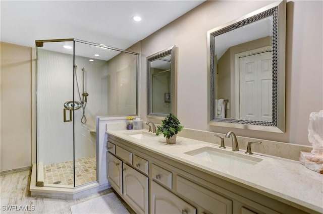 bathroom featuring double vanity, a stall shower, a sink, and recessed lighting