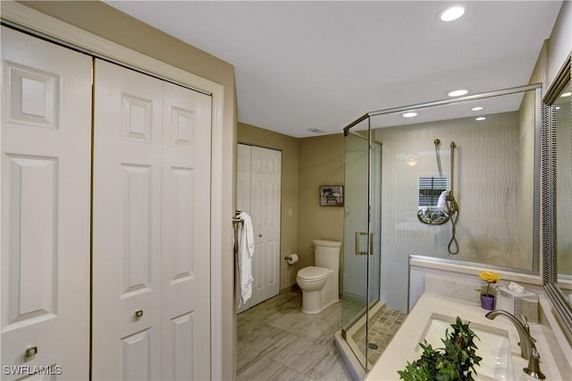 bathroom with a closet, a shower stall, toilet, and vanity