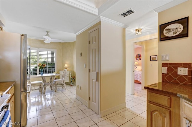 hall with ornamental molding, light tile patterned flooring, visible vents, and baseboards